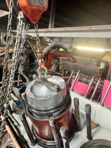 The piston and connecting rod are being lowered through the 'tapered' 'piston pot.'
This device compresses the piston rings as you lower the piston onto the cylinder liner. Photo by Steve Rowston